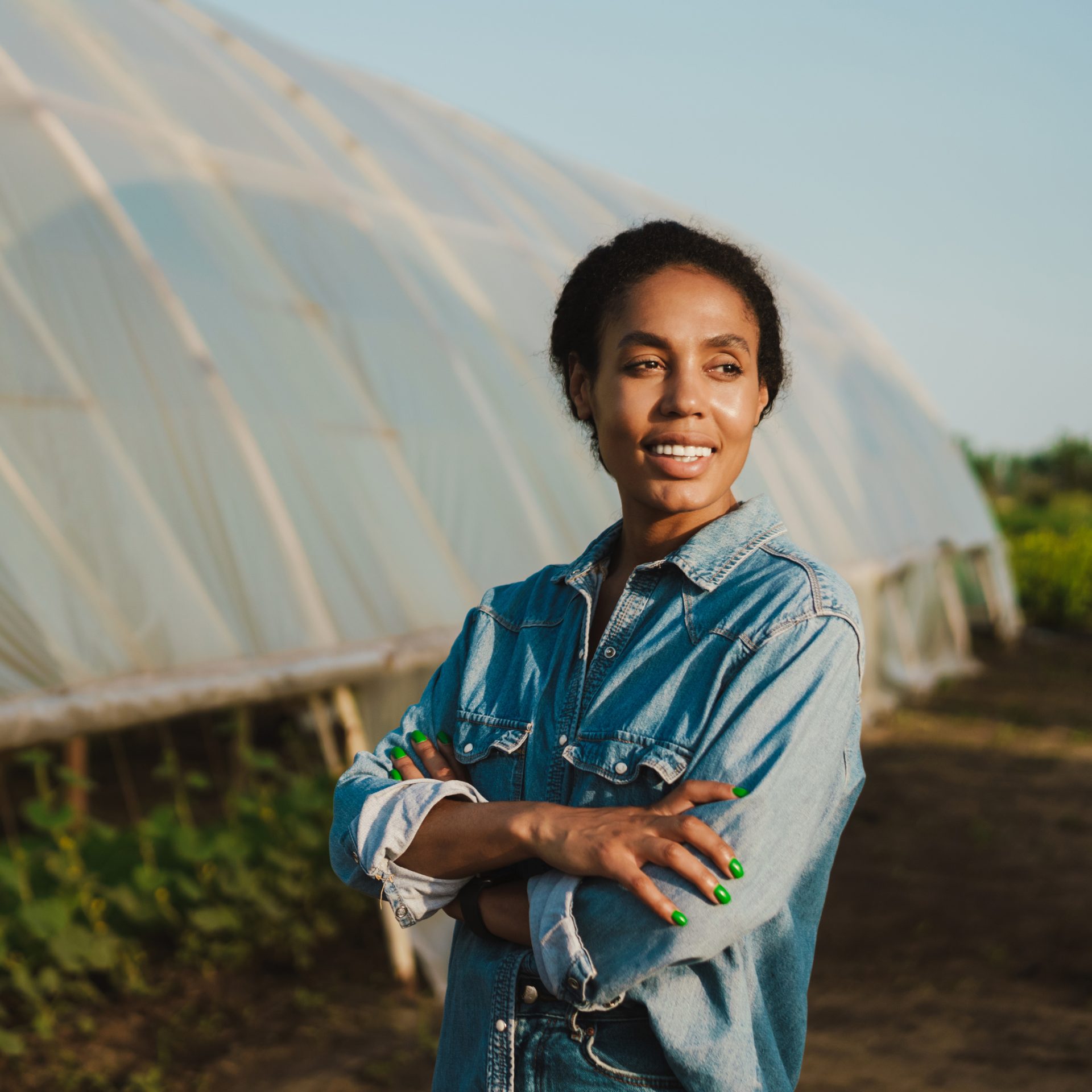 A woman standing with her arms folded outside her farm